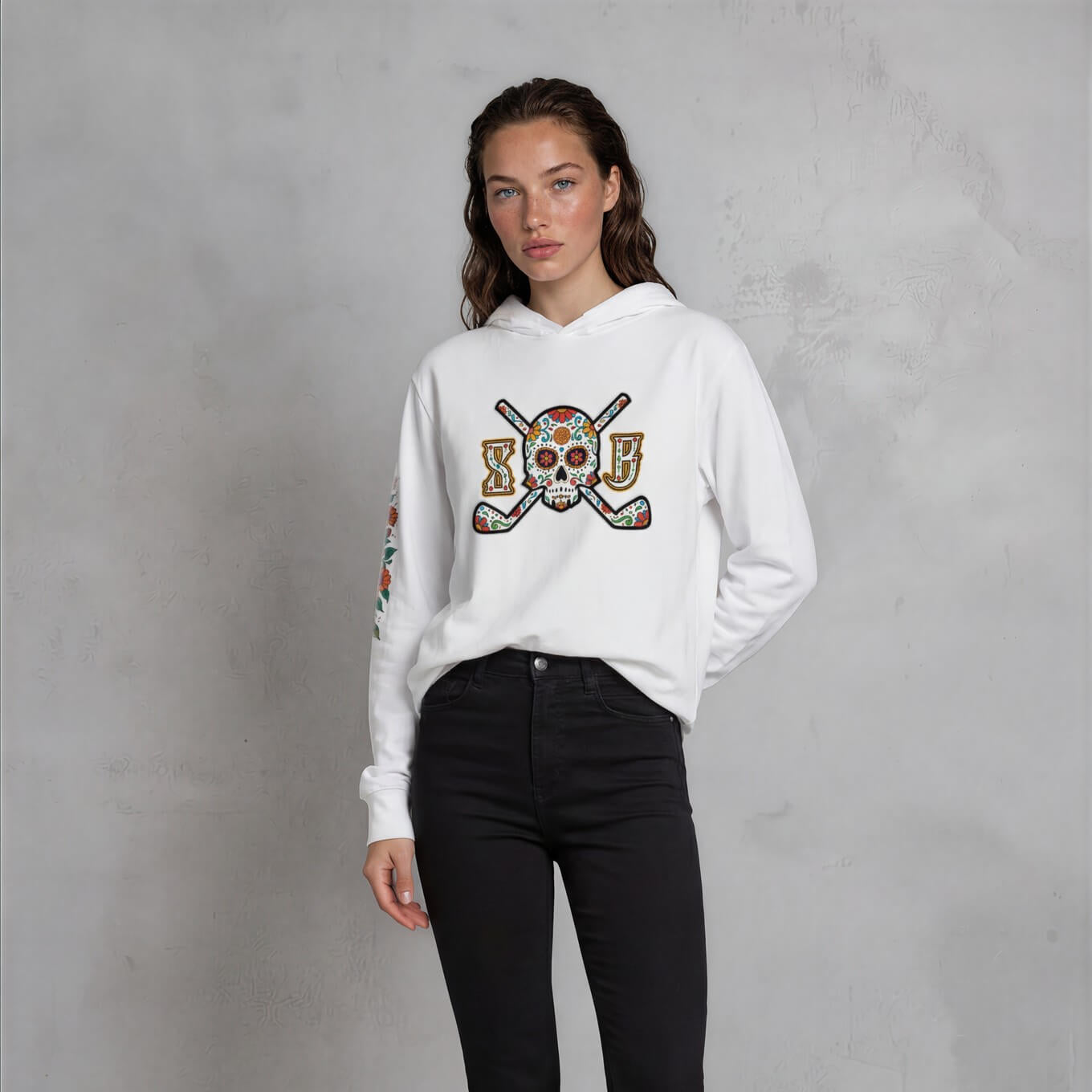 Woman wearing a white hoodie with a graphic design and black pants against a gray background