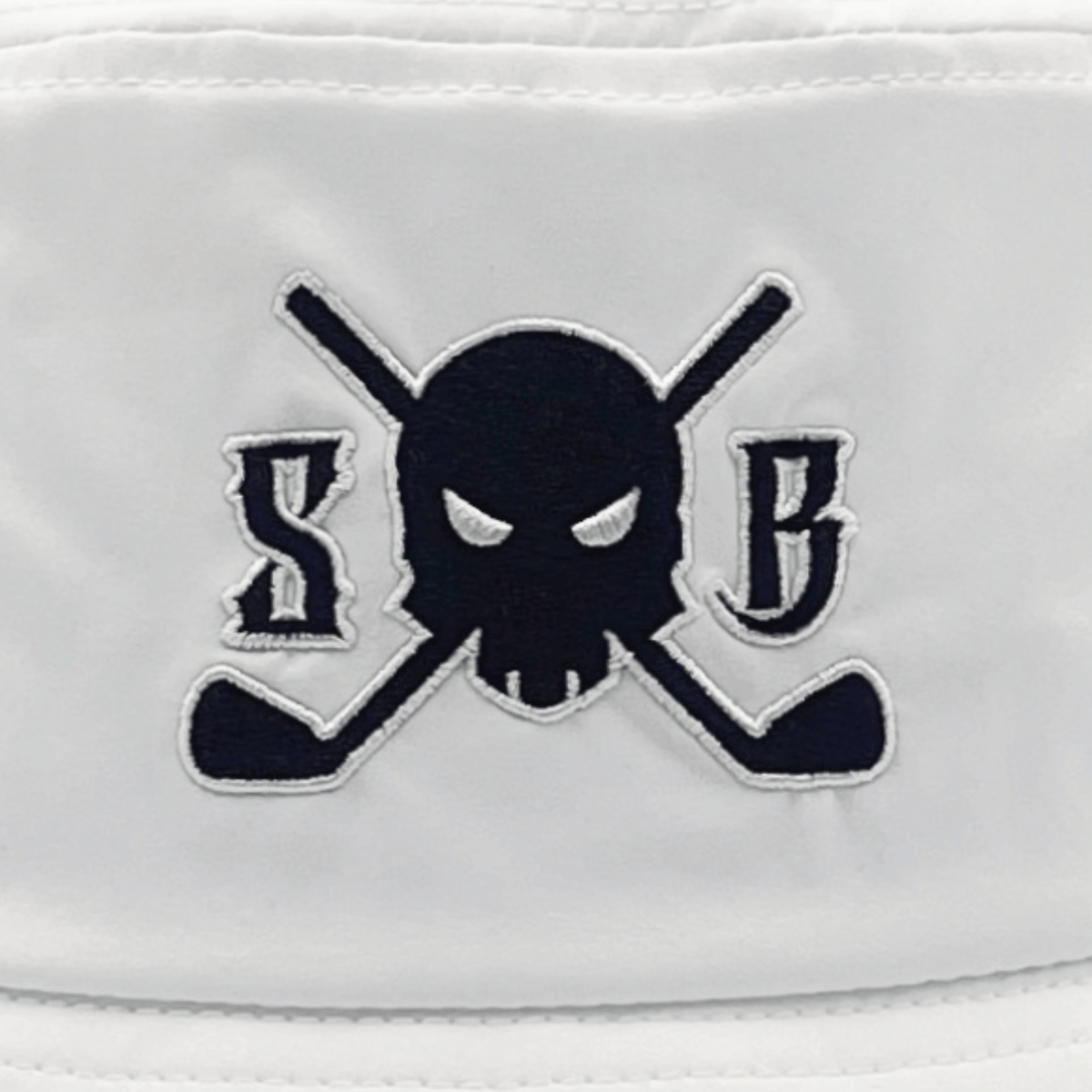 A close-up of a white fabric item featuring an embroidered logo of a black skull with white eyes, flanked by the letters 'S' and 'B' on a background of crossed golf clubs.