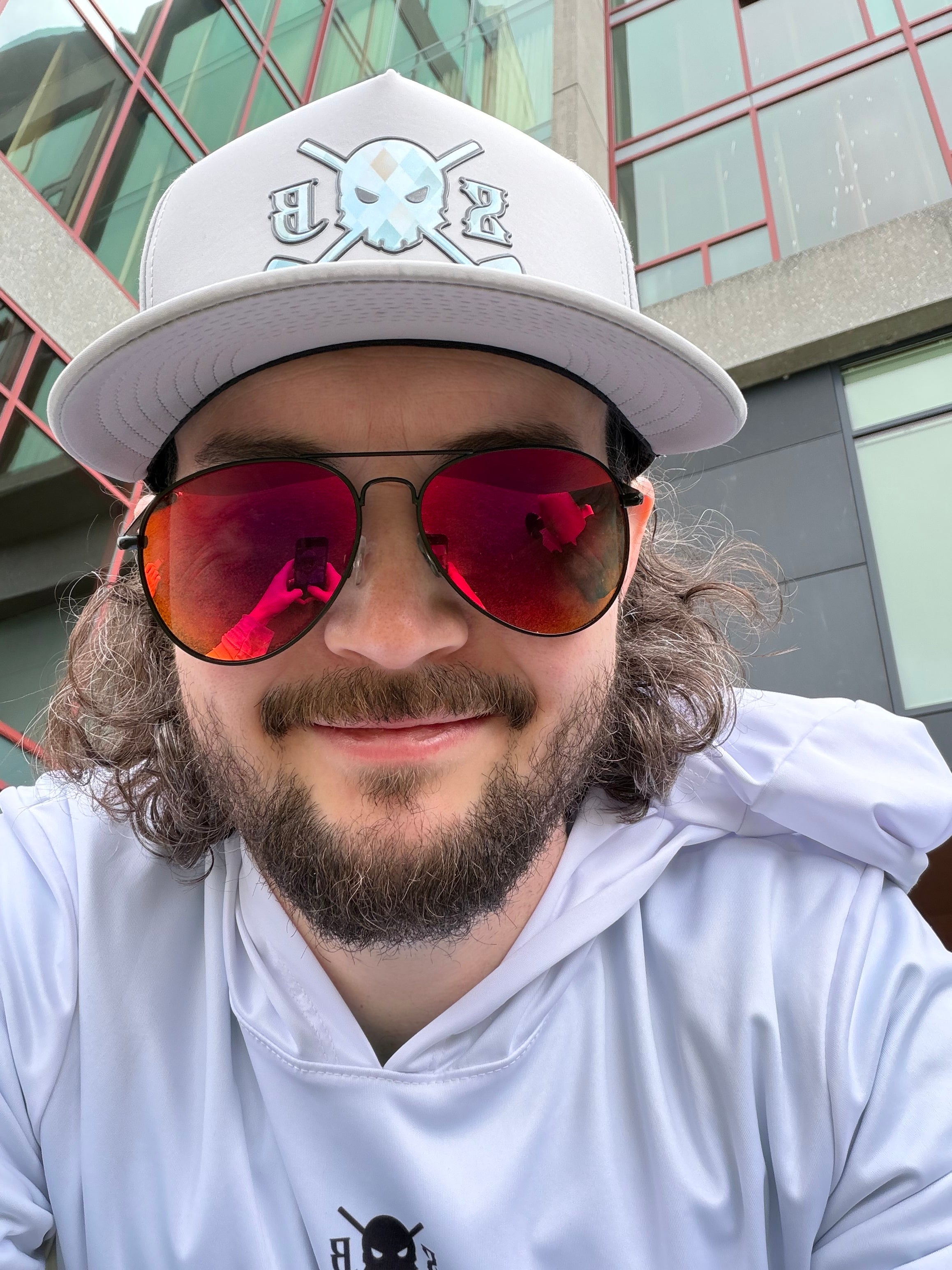 Person wearing a white cap and sunglasses with a building in the background