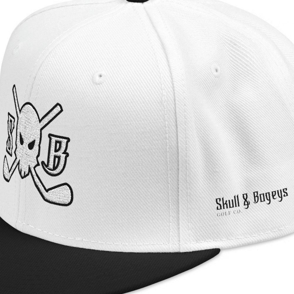 White structured snapback cap with a black flat brim, featuring a black embroidered skull and crossed elements on the front panel and 'Skull & Bageys' branding on the side.