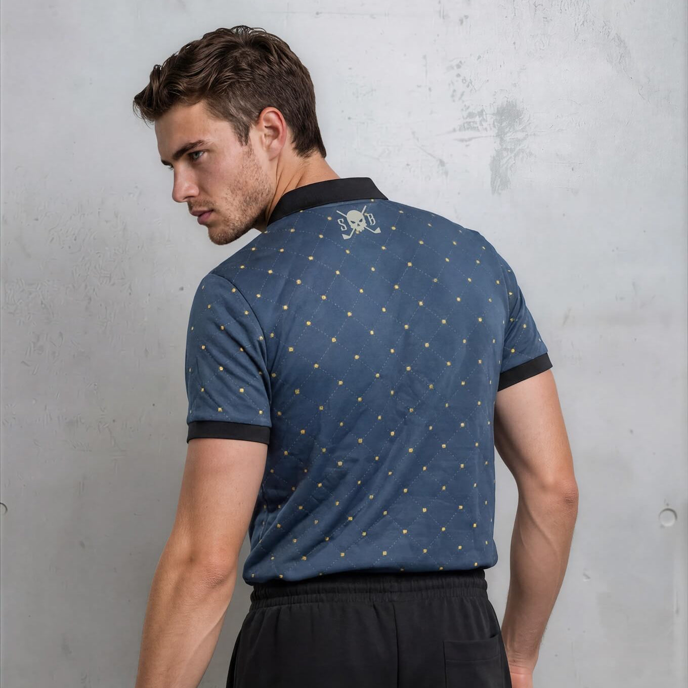 Man wearing a blue patterned polo shirt and black shorts against a gray background
