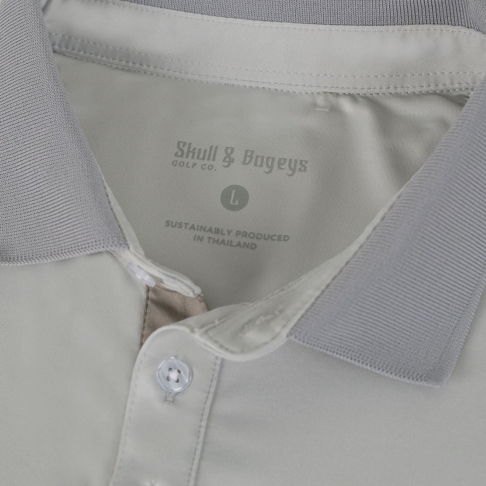 Close-up of a Skull & Bogeys Golf Co. polo shirt collar and inner neck area showing the printed brand label 'Skull & Bogeys Golf Co.' and size 'L'.