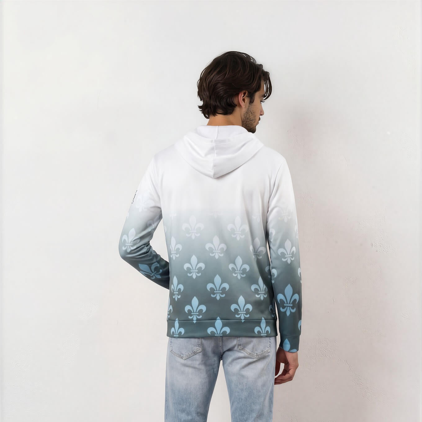 Person wearing a gradient hoodie with a floral pattern and light gray pants against a white background
