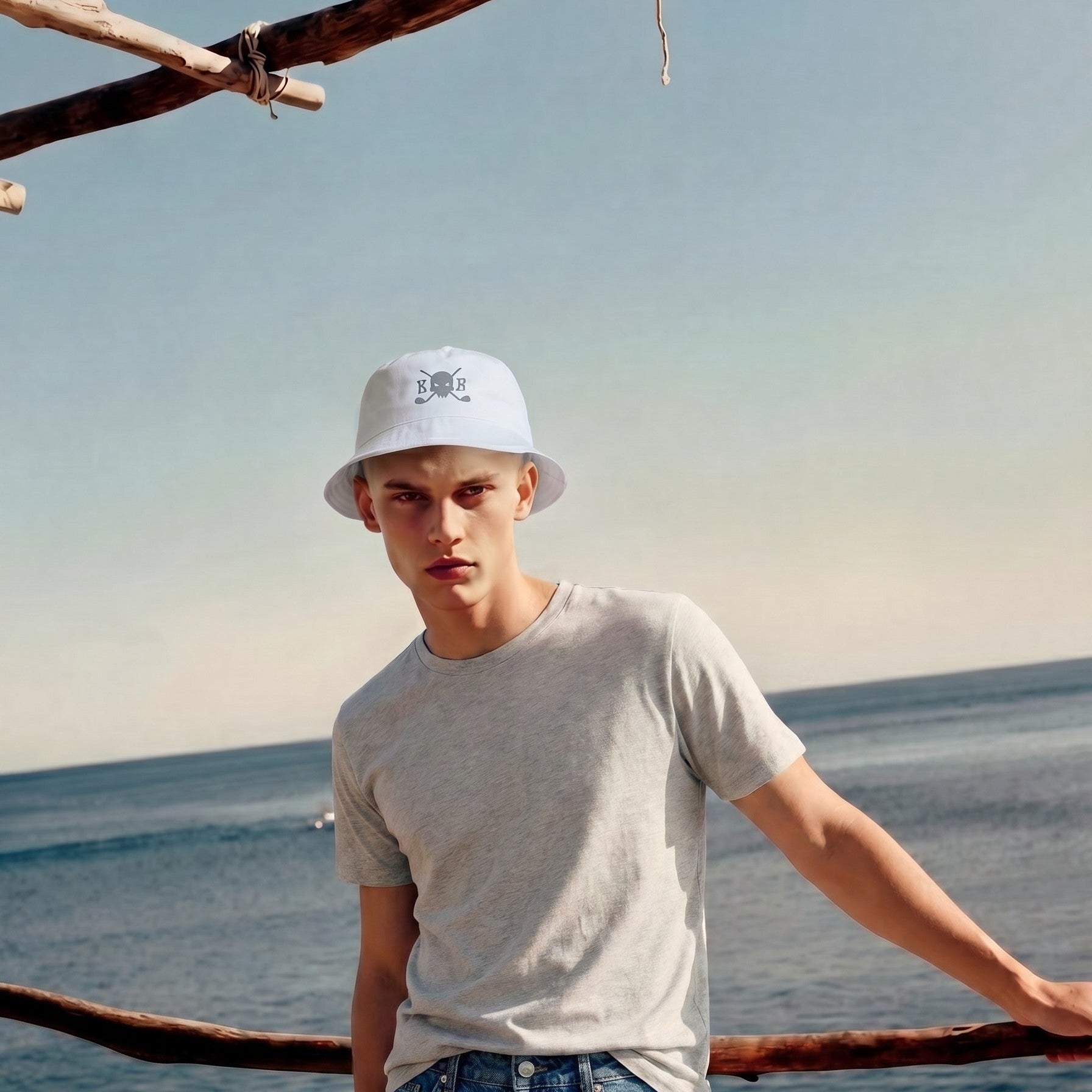 Person wearing a white bucket hat and gray t-shirt by the ocean