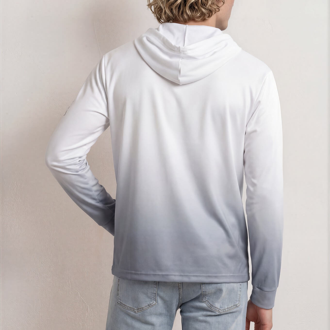 Person wearing a light gray hoodie and jeans against a plain background