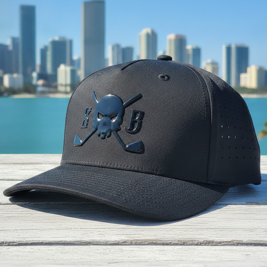 A black baseball cap with a tonal skull and crossed paddles logo featuring the letters 'SB', displayed on a white wooden deck with a blurred Miami skyline and ocean in the background.