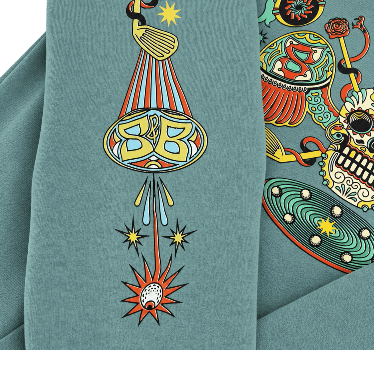 Close-up of an Arctic blue fabric garment featuring a colorful graphic print with a golf club, striped cone, stars, and a skull motif on the sleeve.