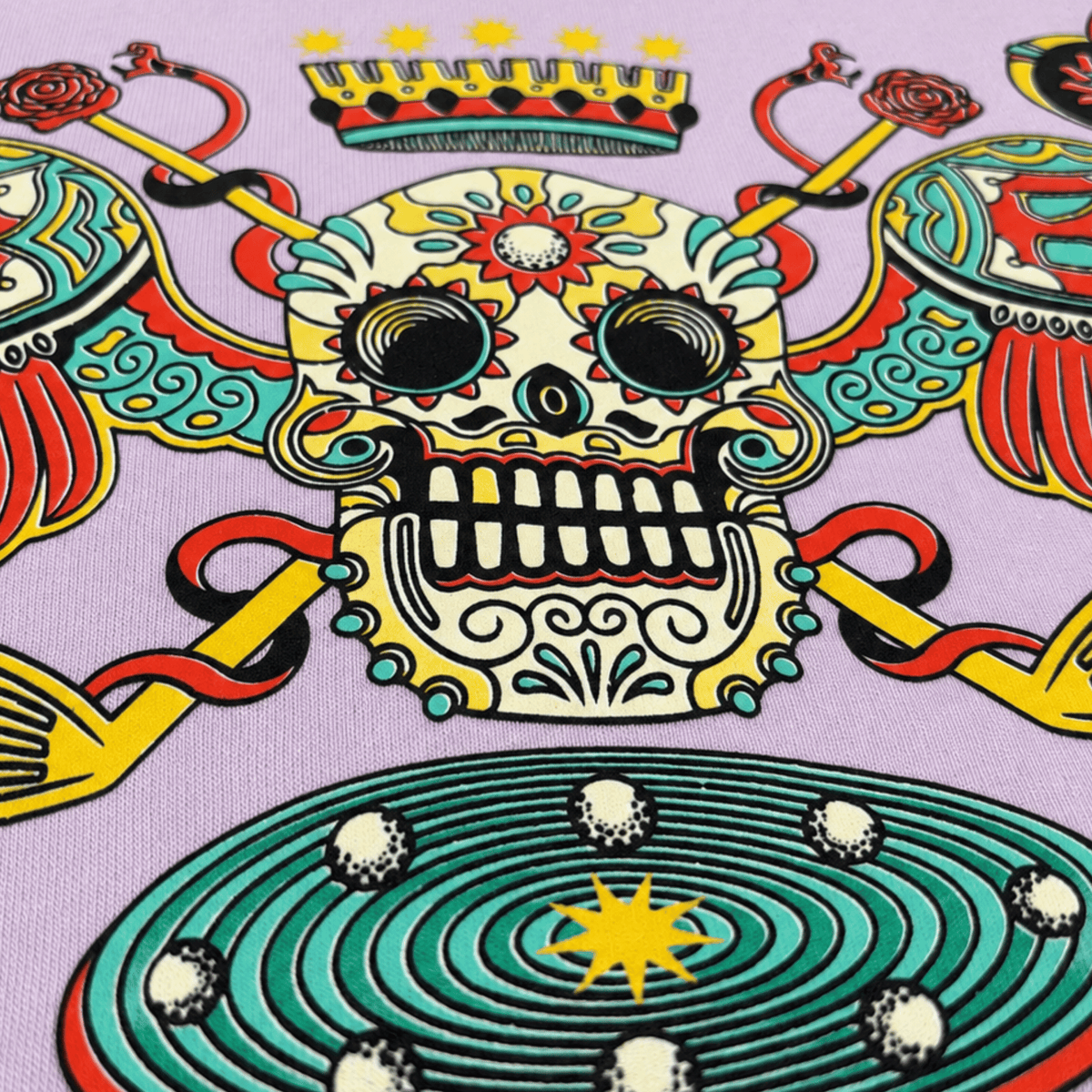 A close-up of a colorful printed fabric featuring a Day of the Dead sugar skull design on a light lavender background.