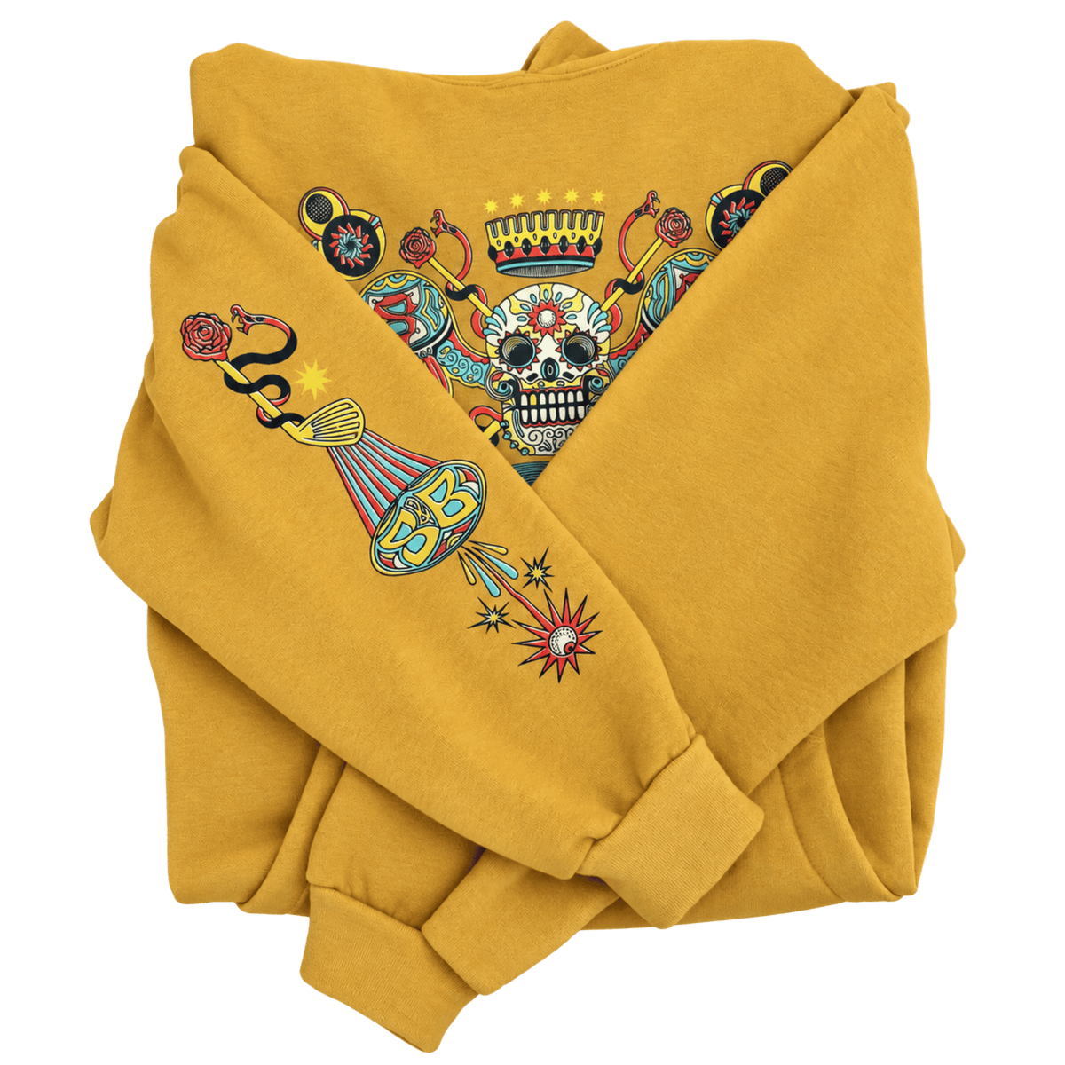 A folded mustard yellow sweatshirt featuring a colorful graphic print on the chest and sleeve. The graphic depicts a sugar skull under a crown, a snake, a teardrop, and a starburst in red, blue, black, and white.