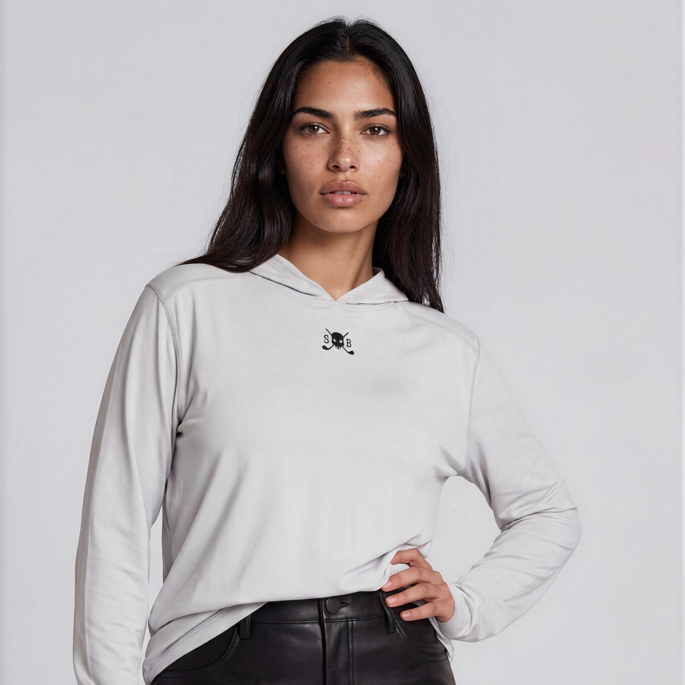 Woman wearing a light gray hoodie with a small logo and a black leather skirt on a white background
