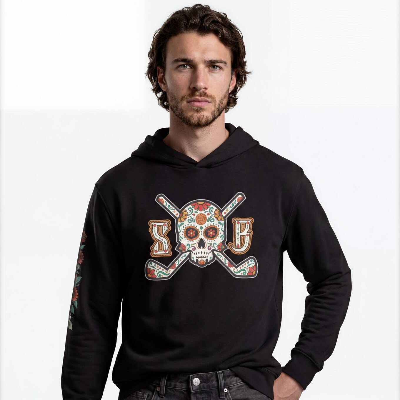 Man wearing a black hoodie with a colorful skull and crossbones design on a white background