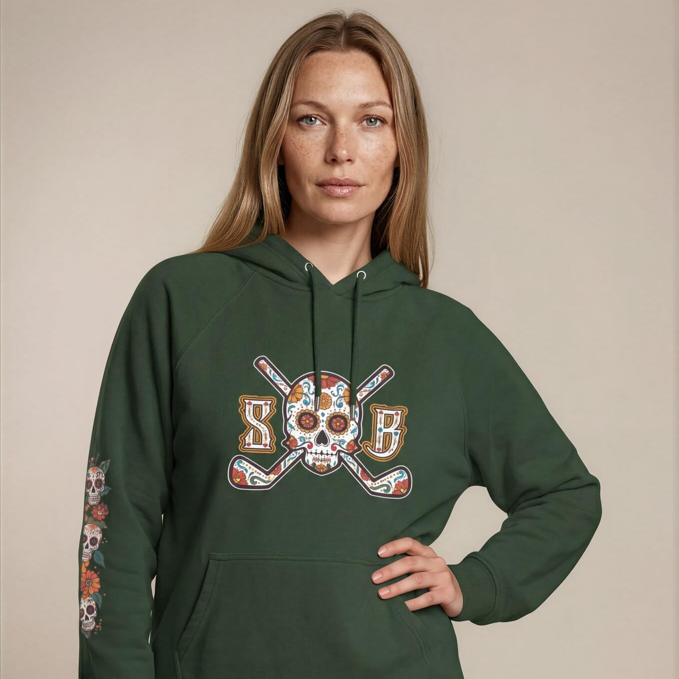 Woman wearing a green hoodie with a skull and crossbones design on a beige background
