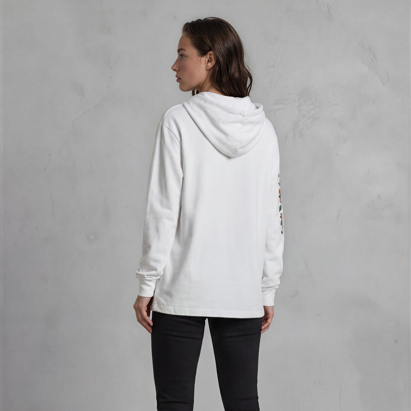 Person wearing a white hoodie and black pants against a gray background